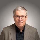 Portraitfoto von Jürgen Frömmrich vor grauem Hintergrund.