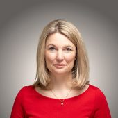 Portraitfoto von Kathrin Anders vor grauem Hintergrund.