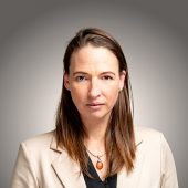 Portraitfoto von Katrin Schleenbecker vor grauem Hintergrund.