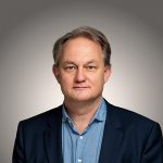 Portraitfoto von Marcus Bocklet vor grauem Hintergrund.