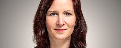 Portraitfoto von Kaya Kinkel vor grauem Hintergrund.