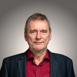 Portraitfoto von Hans-Jürgen Müller vor grauem Hintergrund.