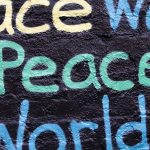 Symbolbild Frieden und Internationales - Schriftzug "World Peace" gesprüht in verschiedenen Farben auf schwarzem Grund.