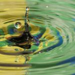Symbolbild Queerpolitik - Regenbogenfahne gespiegelt in Wasseroberfläche mit Tropfen